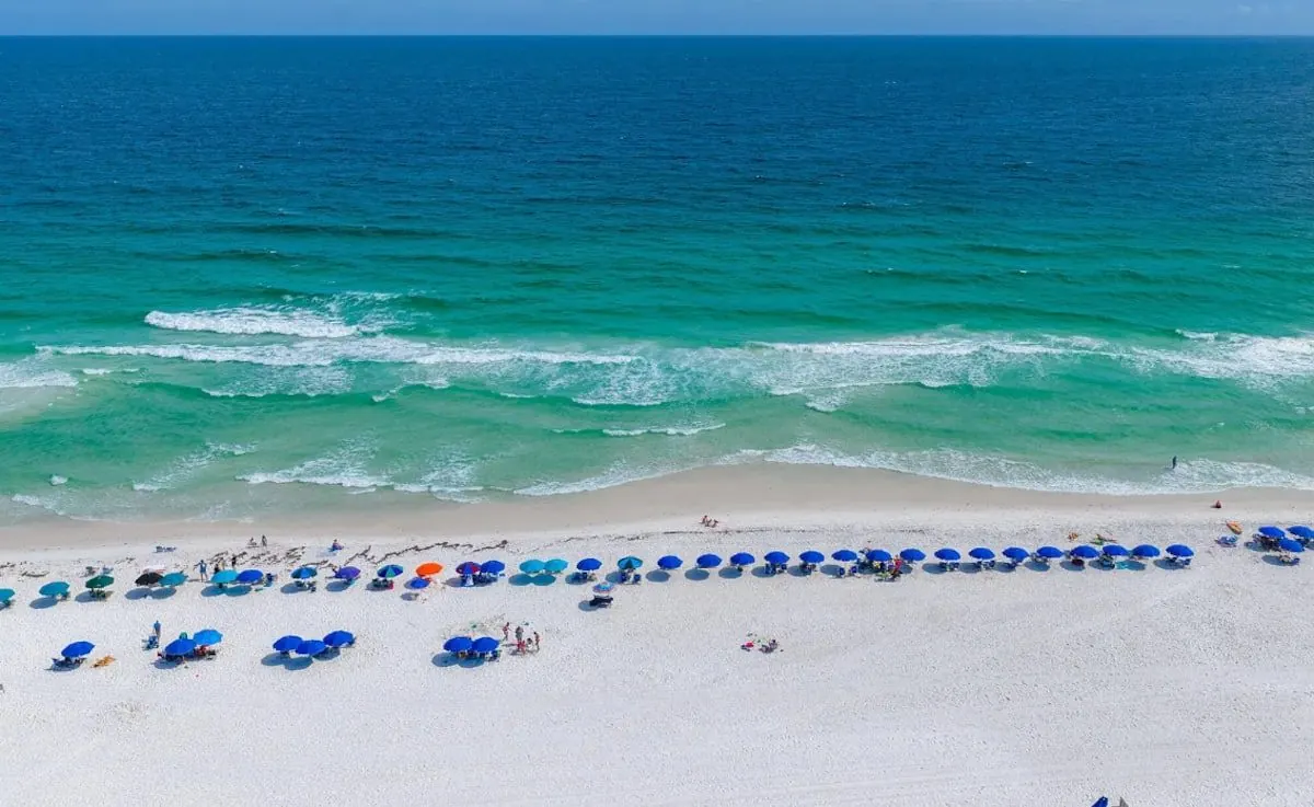 White-sand beach with turquoise water and blue umbrellas