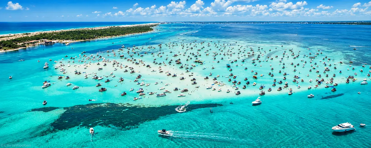 Aerial view of hundreds of boats anchored on a turquoise sandbar in the bay