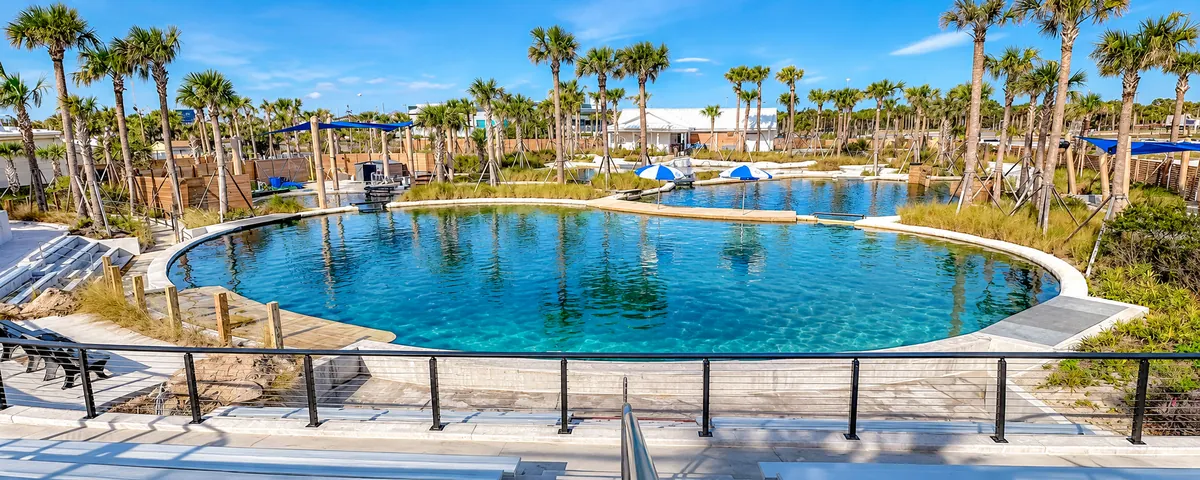 Dolphin Oasis lagoon pools surrounded by palm trees, with shade umbrellas and viewing areas