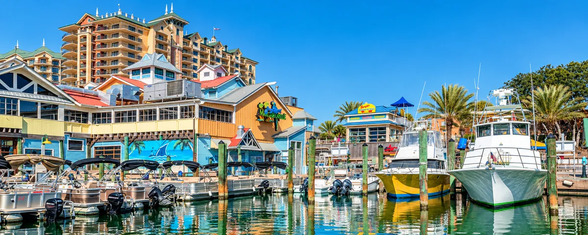Waterfront restaurants and docked boats at HarborWalk Village with the Emerald Grande tower behind